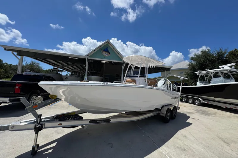 Slide: The Image of 2026 NauticStar 231 Hybrid boat on trailer, parked outdoors under a clear blue sky. - 3