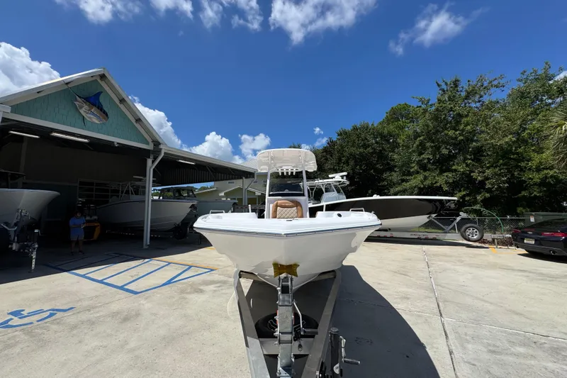 Slide: The Image of 2026 NauticStar 231 Hybrid boat on trailer at dealership under blue sky. - 5