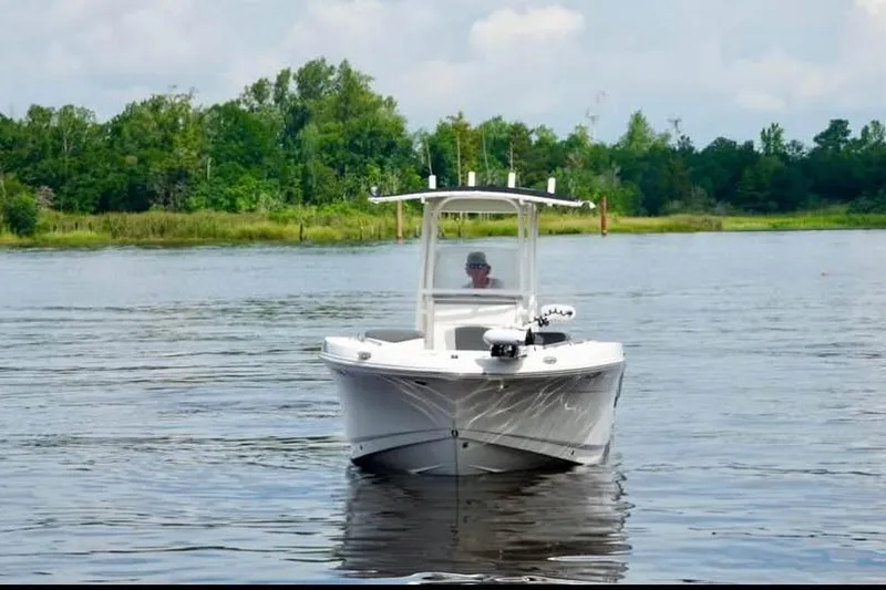 Slide: The Image of 2023 Robalo R200 Center Console boat on a calm lake with lush greenery. - 13