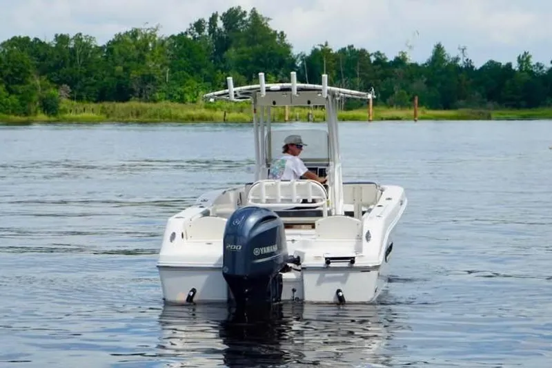 Slide: The Image of 2023 Robalo R200 Center Console boat on a calm lake with trees in the background. - 15