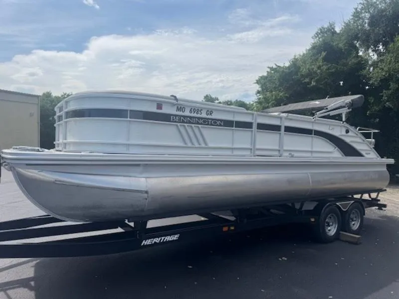 Slide: The Image of 2022 Bennington 25 LSB pontoon boat on trailer, parked outdoors. - 16