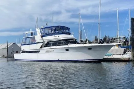 The Image of 1990 Carver Californian 55 yacht docked in a marina, featuring a sleek white design. - 0