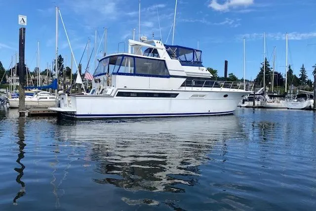 Slide: The Image of 1990 Carver 55 yacht docked in a marina with clear blue skies. - 1