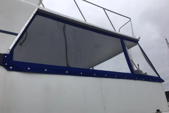 Slide: The Image of 1990 Carver 55 boat with blue-trimmed window, overcast sky background. - 10