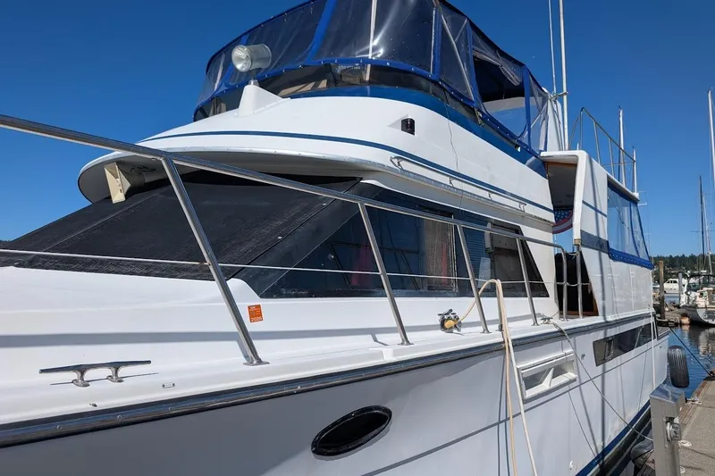 Slide: The Image of 1990 Carver 55 yacht docked, featuring sleek design and blue accents under clear sky. - 4