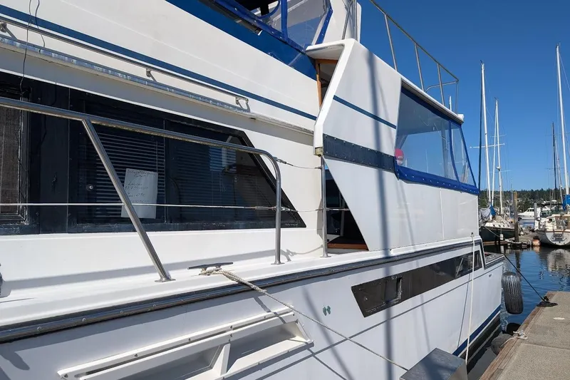 Slide: The Image of 1990 Carver 55 yacht docked at marina, featuring sleek white and blue design. - 5