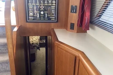 Slide: The Image of Interior of a 1990 Carver 55 yacht, featuring wooden cabinetry and a framed nautical knot display. - 28