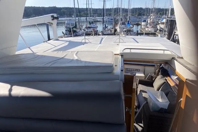 Slide: The Image of 1990 Carver 55 yacht interior with marina view, featuring cushioned seating and open deck. - 36