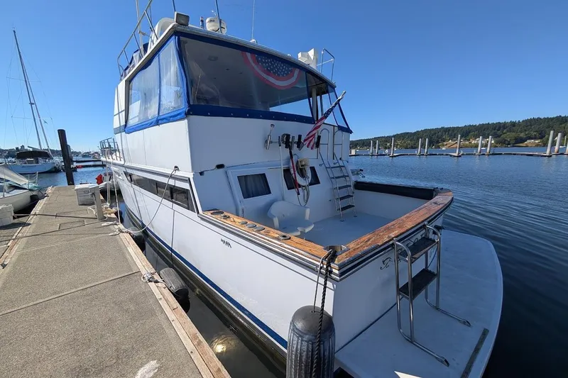 Slide: The Image of 1990 Carver 55 yacht docked at marina, featuring spacious deck and blue canopy. - 7