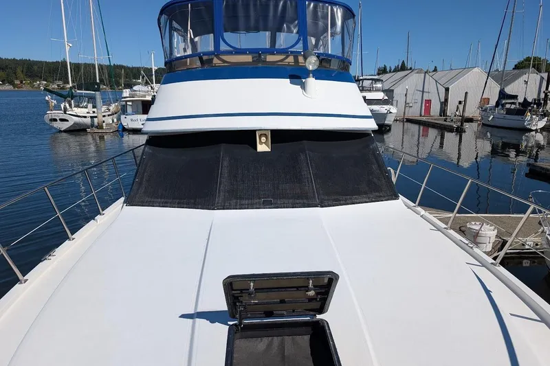 Slide: The Image of 1990 Carver 55 yacht docked at marina, featuring spacious deck and blue accents. - 8