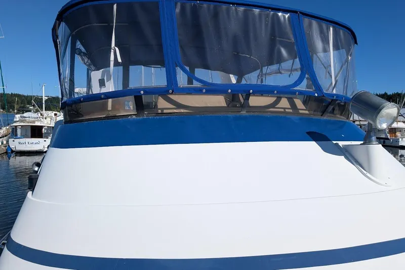 Slide: The Image of 1990 Carver 55 yacht with blue canopy docked in marina under clear sky. - 9