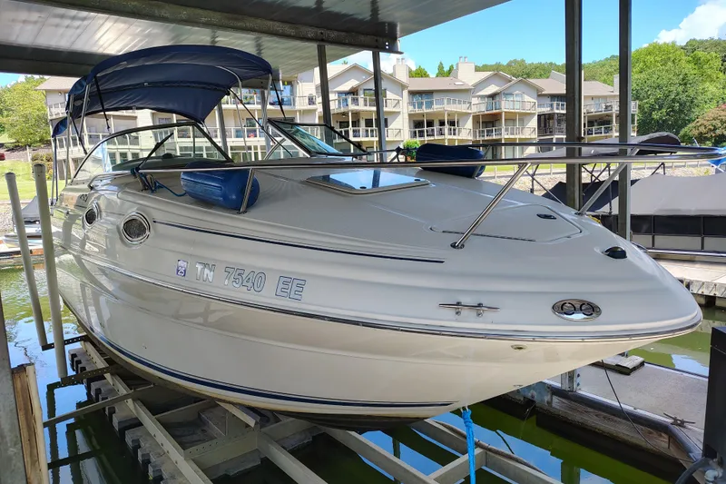 Slide: The Image of 2000 Sea Ray 240 Sundancer boat docked, featuring sleek design and blue canopy. - 4