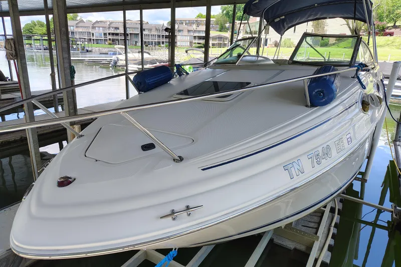 Slide: The Image of 2000 Sea Ray 240 Sundancer docked in a marina, featuring sleek design and blue fenders. - 6