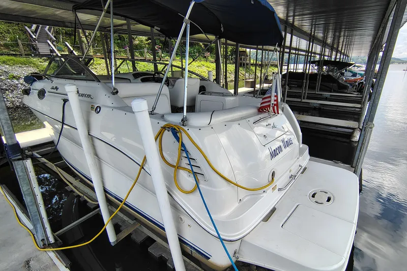 Slide: The Image of 2000 Sea Ray 240 Sundancer docked under a covered marina, featuring an American flag. - 8