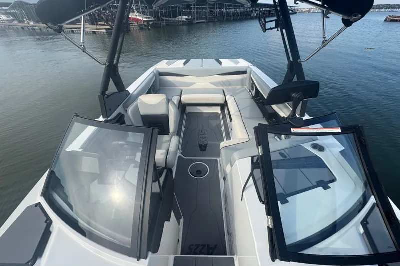 Slide: The Image of 2023 Axis A225 boat interior with sleek seating and open windshield on water. - 10