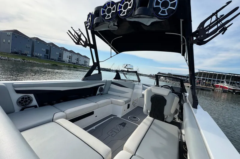 Slide: The Image of 2023 Axis A225 boat interior with speakers, docked near waterfront homes. - 23