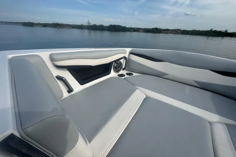 Slide: The Image of 2023 Axis A225 boat interior with gray seating, cup holders, and speaker on a calm lake. - 8