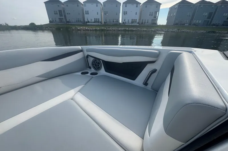 Slide: The Image of 2023 Axis A225 boat interior with sleek seating and speaker, near waterfront homes. - 9