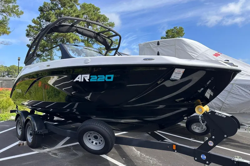 Slide: The Image of 2025 Yamaha Boats AR220 on trailer, sleek black design, parked outdoors. - 0