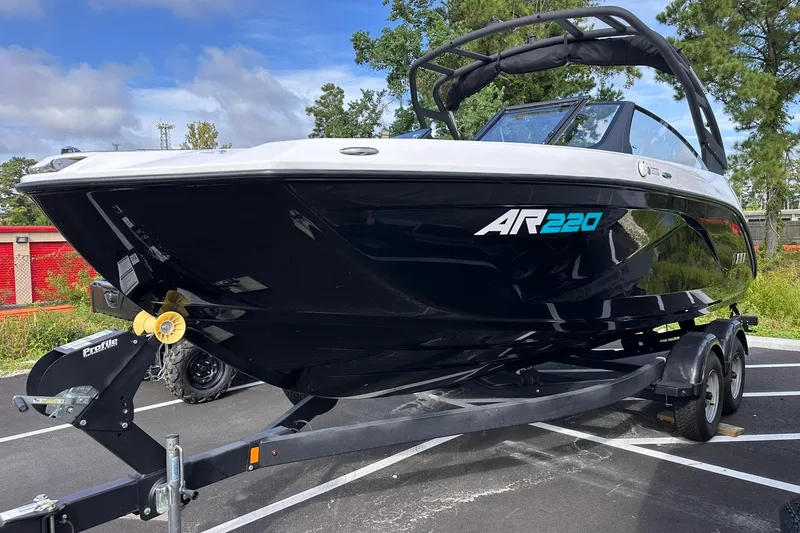Slide: The Image of 2025 Yamaha Boats AR220 on trailer, sleek black design, parked outdoors. - 1