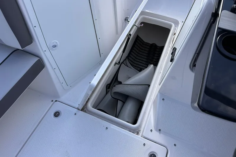 Slide: The Image of 2025 Yamaha Boats AR220 storage compartment with open hatch, showcasing interior space and seating. - 21
