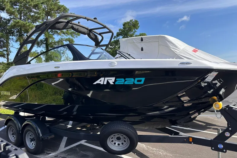Slide: The Image of 2025 Yamaha Boats AR220 on trailer, sleek black design, parked outdoors. - 25