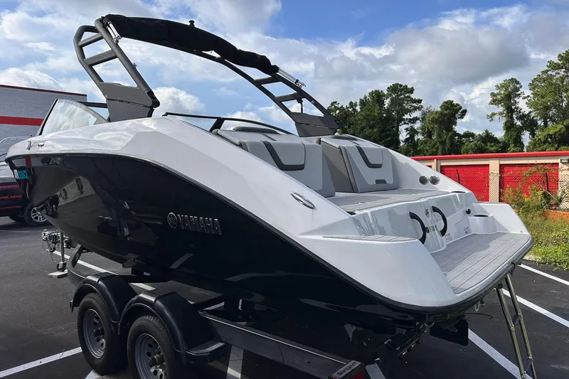 Slide: The Image of 2025 Yamaha Boats AR220 on trailer, sleek design, parked outdoors under cloudy sky. - 5