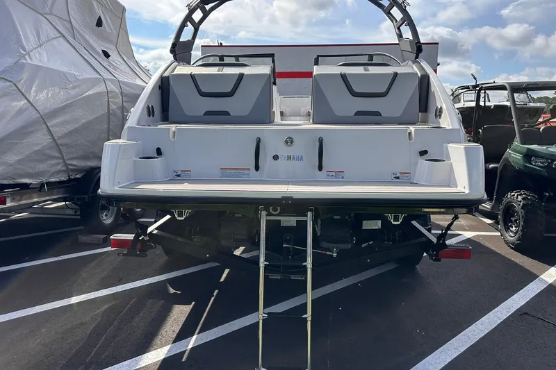 Slide: The Image of 2025 Yamaha Boats AR220, rear view, parked in a lot with ladder extended. - 7
