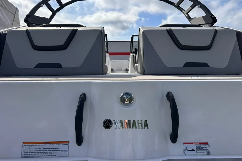 Slide: The Image of 2025 Yamaha Boats AR220 rear view with seating and logo, under a partly cloudy sky. - 8