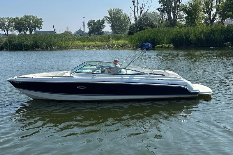 Slide: The Image of 2005 Formula 260 Bowrider boat cruising on a calm lake with lush greenery. - 1