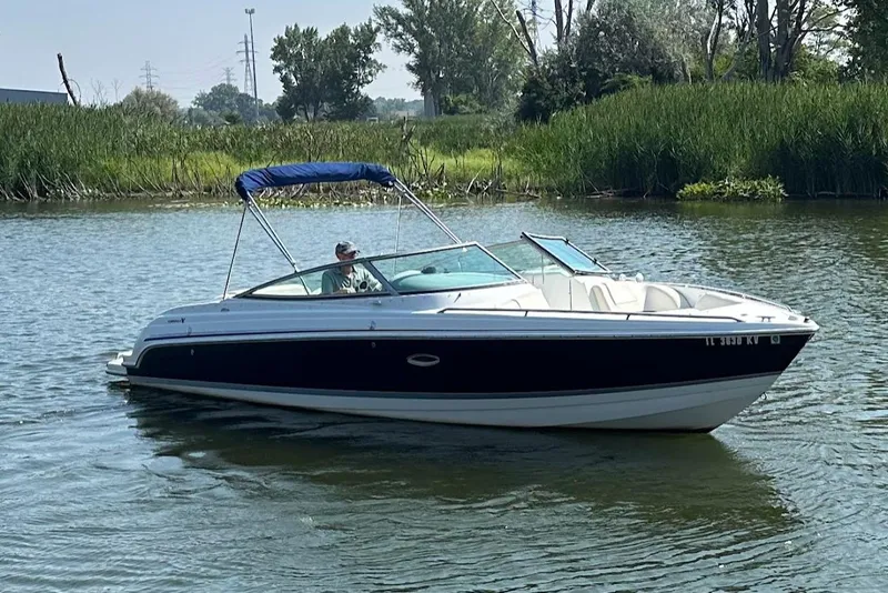Slide: The Image of 2005 Formula 260 Bowrider boat cruising on a calm lake with lush greenery. - 6