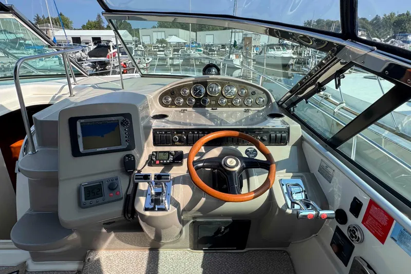 Slide: The Image of 2002 Cruisers Yachts 3870 Express helm with wooden steering wheel and navigation instruments. - 13