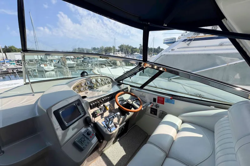 Slide: The Image of 2002 Cruisers Yachts 3870 Express helm with steering wheel and control panel, docked at marina. - 19
