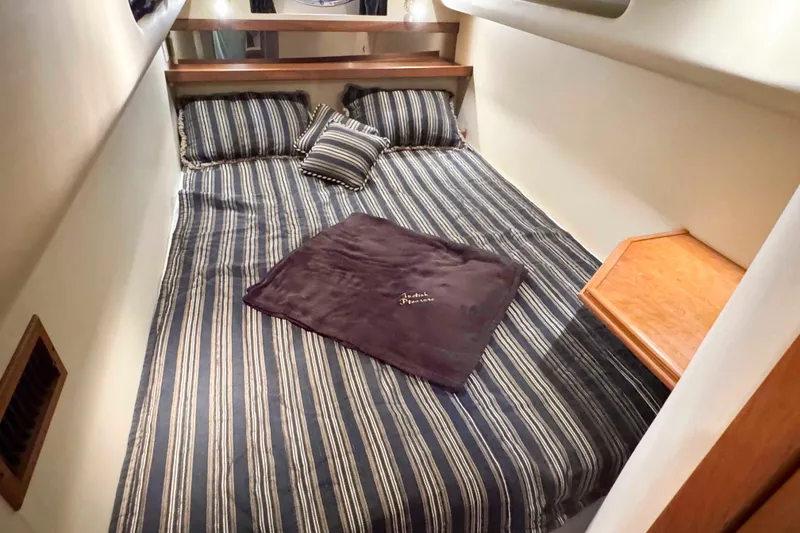 Slide: The Image of 2002 Cruisers Yachts 3870 Express cabin with striped bedding and wooden accents. - 31