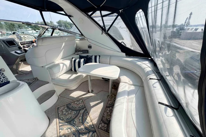 Slide: The Image of 2002 Cruisers Yachts 3870 Express interior with white seating and table, featuring nautical decor. - 7