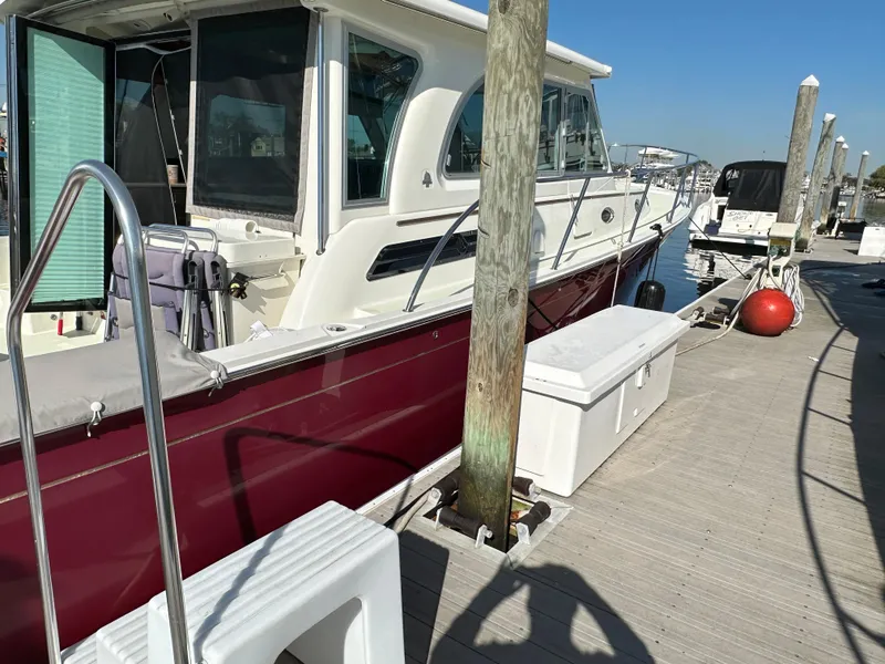Slide: The Image of 2017 Back Cove 41 boat docked at marina, featuring sleek design and maroon hull. - 12