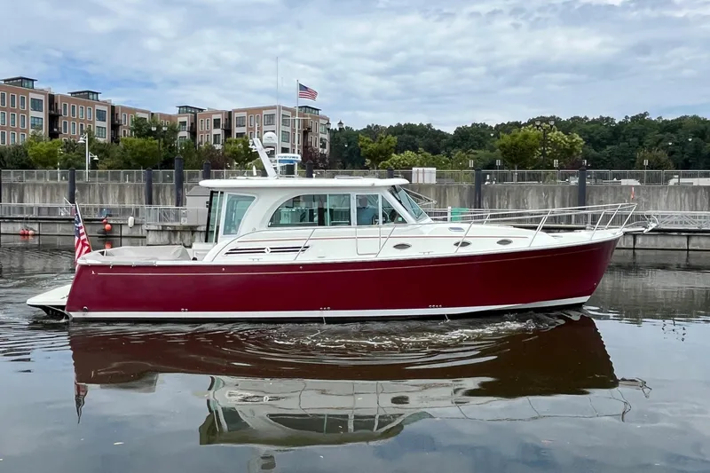 Slide: The Image of 2017 Back Cove 41 boat with red hull, docked near modern buildings. - 124