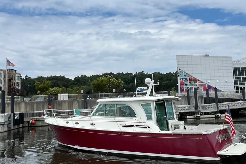 Slide: The Image of 2017 Back Cove 41 boat with red hull docked in a marina, American flag displayed. - 125