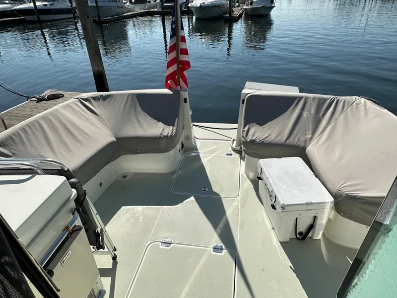 Slide: The Image of 2017 Back Cove 41 boat deck with seating, cooler, and American flag at marina. - 21
