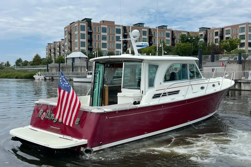 Slide: The Image of 2017 Back Cove 41 boat with American flag, docked near modern buildings. - 3
