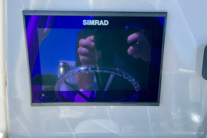 Slide: The Image of Simrad display on 2023 Trophy T24CC boat dashboard, reflecting steering wheel and hands. - 13