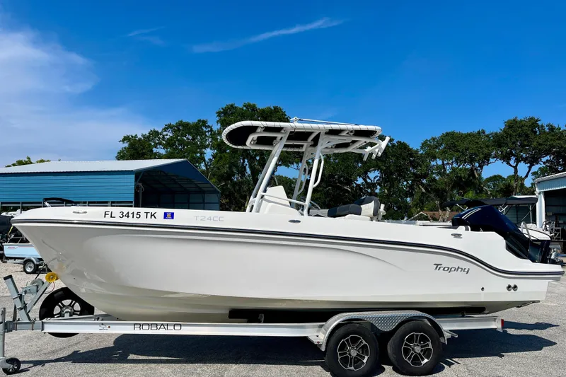 Slide: The Image of 2023 Trophy T24CC boat on trailer, parked outdoors under clear blue sky. - 4