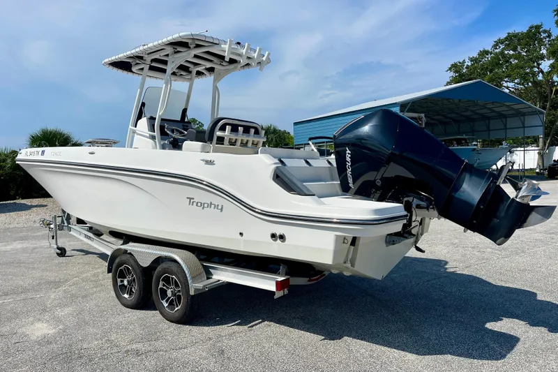 Slide: The Image of 2023 Trophy T24CC boat on trailer with Mercury outboard motor, parked outdoors. - 5