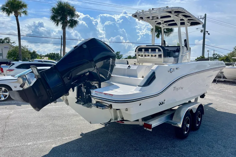 Slide: The Image of 2023 Trophy T24CC boat on trailer, featuring powerful outboard motor, parked outdoors. - 6