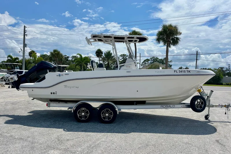 Slide: The Image of 2023 Trophy T24CC boat on trailer, parked outdoors under a clear blue sky. - 7