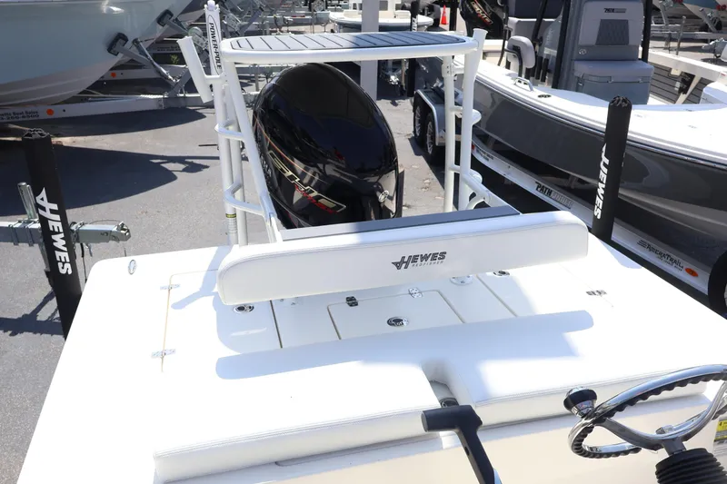 Slide: The Image of 2025 Hewes Redfisher 18 boat, rear view with motor and steering wheel, in a showroom. - 2