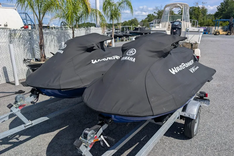 Slide: The Image of 2021 Yamaha WaveRunner VX Deluxe jet skis covered on trailers, parked outdoors. - 15