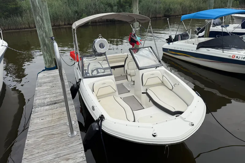 Slide: The Image of 2020 Stingray 192 SC boat docked, featuring spacious seating and canopy. - 2