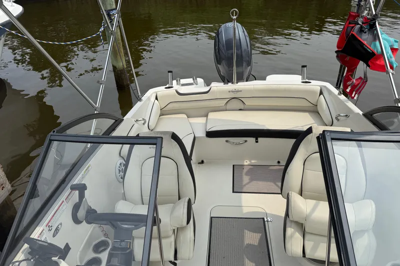 Slide: The Image of 2020 Stingray 192 SC boat interior with beige seating and steering wheel, docked on calm water. - 5