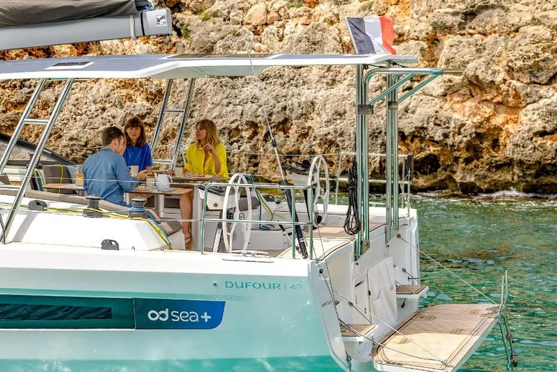 Slide: The Image of People enjoying leisure time on a 2026 Dufour 48 yacht near rocky coastline. - 10